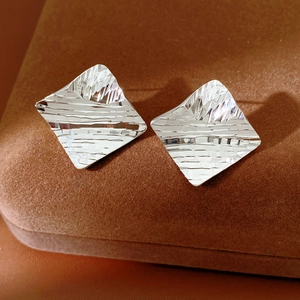 Detailed close-up of geometric square earrings with a hammered silver texture finish