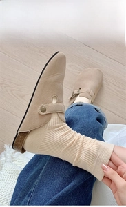 Close-up of beige suede mules with cork sole paired with socks and denim jeans