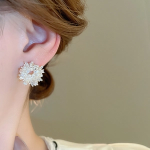 Close-up of elegant flower stud earring with pearls and zircon crystals on ear