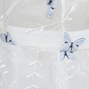 Détail macro du chapeau en dentelle blanche avec broderies papillon 3D bleues