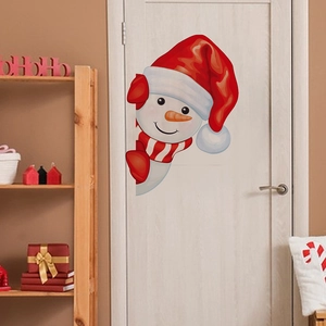 Peeking snowman Christmas wall decal on a white door with cozy holiday decorations