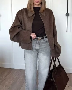 Détail d'une veste courte en laine marron foncé avec col à revers et fermeture éclair