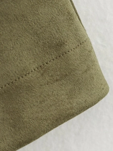 Macro shot of olive green suede fabric showing smooth texture and professional stitching