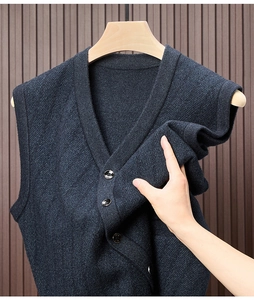 Detail der Strickstruktur einer dunkelblauen V-Ausschnitt-Weste am Holzbügel