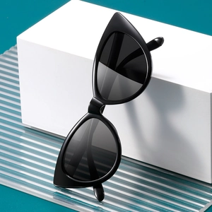 Classic black cat-eye sunglasses with glossy frame displayed on a modern geometric stand