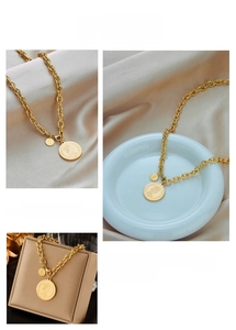 Detail of vintage gold coin pendant necklace shown on silk and decorative trays