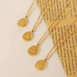 Golden titanium steel beaded necklaces with engraved pebble pendants on beige background
