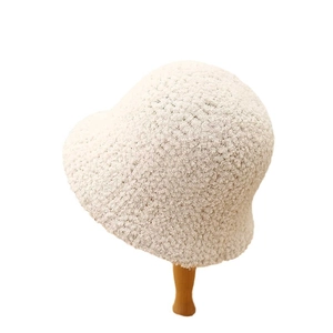 Creamy white lamb wool bucket hat for women on a wooden stand with soft plush texture