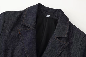 Detalle de chaqueta vaquera azul oscuro con costuras naranjas y cuello de solapa clásico