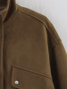 Gros plan sur une veste en daim marron avec boutons-pression et détails aux épaules