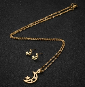 Détail d'une parure dorée avec pendentifs lune et étoile évidés sur fond texturé noir