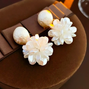 Macro shot of elegant cream pearl and white floral cluster stud earrings on a jewelry box