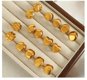 Collection de boucles d'oreilles en acier titane doré dans un écrin à bijoux