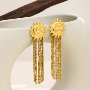 Gold stainless steel sun face tassel earrings hanging on a white ceramic display stand