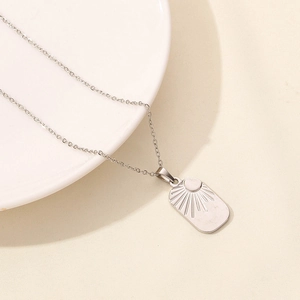 Close-up of a silver stainless steel rectangular pendant with sun embossed pattern