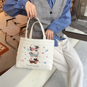 Detail of white quilted handbag with heart stitching and cute embroidered dog design