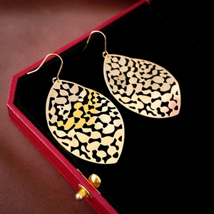 Close-up of golden hollow leaf tassel earrings displayed in a luxury red velvet jewelry box