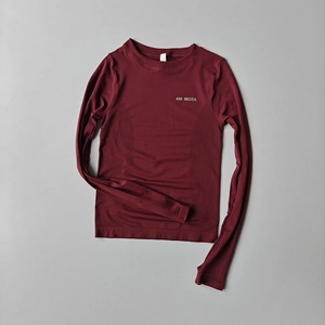 Detail of burgundy long sleeve yoga top featuring seamless texture and logo print
