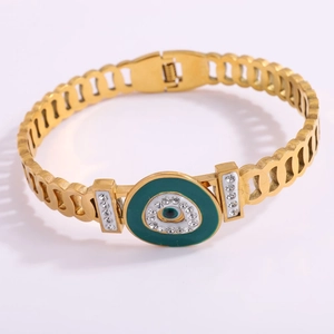 Close-up of gold-plated stainless steel bracelet featuring green evil eye and rhinestones