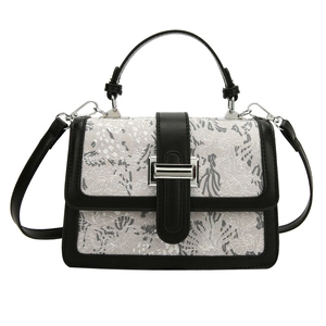 Elegant white floral lace crossbody bag with black leather trim and silver metal lock