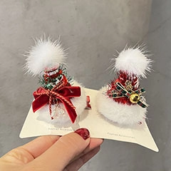 Detail of red Christmas hair clips with white pompoms and green bows for girls