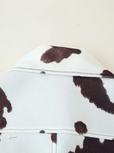 Macro detail of cow print denim jacket showing the collar and brown pattern texture