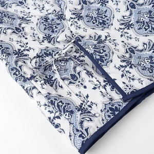 Detail of blue and white paisley pattern fabric with waist tie on winter long sleeve coat