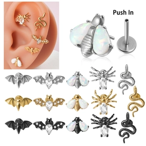 Détail de piercings labret push-in avec motifs araignée et abeille en acier