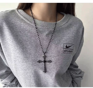 Close-up of gothic cross pendant with black gem on beaded long necklace for women