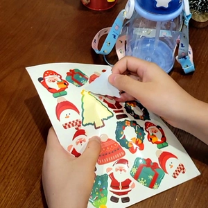 Cartoon Christmas stickers featuring Santa and trees applied to a blue water bottle