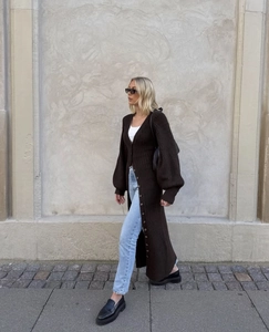 Détail d'un long cardigan en maille marron avec boutonnage simple et manches lanternes
