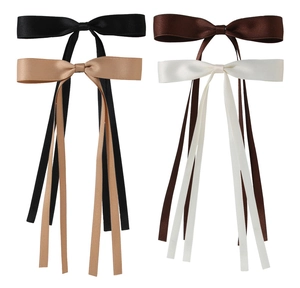 Detailed view of layered satin bow hair clips with long ribbons in four classic colors