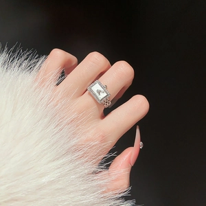 Detailed shot of a silver watch-shaped ring with cubic zirconia on white fur