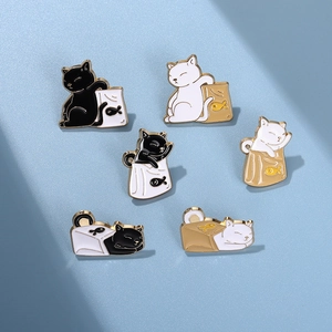 Detailed close-up of six cartoon cat enamel pins in black and white styles with gold edges