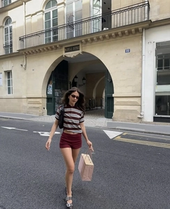 Dettaglio di polo corta a righe e pantaloncini bordeaux slim fit su una modella