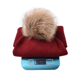 Solid burgundy knit beanie with a detachable faux fur pompom weighing 142g on scale