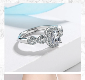 Detail of silver square zircon ring with twisted band on marble and blue ribbon