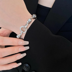 Dettaglio bracciale di perle argento con chiusura in zircone su manica di abito nero