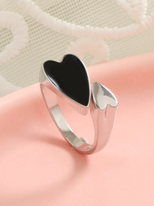 Close-up of silver-tone double heart ring with black enamel inlay on elegant lace background