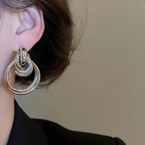 Detailed view of silver layered hoop earrings in polished metal on a female model