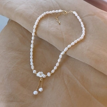 Close-up of freshwater pearl necklace with 14k gold-plated flower pendant on silk