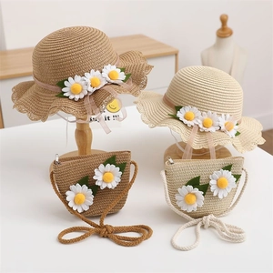 Detail of hand-woven straw hat and matching crossbody bag with white daisy accents