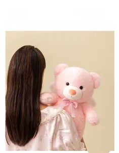 Detailed view of pink angel teddy bear with soft fur and decorative checkered ribbon bow