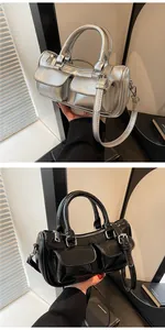 Detail view of metallic silver and glossy black saddle bags with front buckle pockets