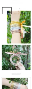 Dettaglio di bracciali in resina glitterata oro e argento con nastro di seta