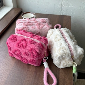 Detailed view of plush makeup bags with 3D heart patterns and sturdy fabric handles