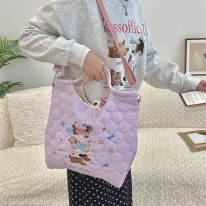 Detail of purple quilted shoulder bag featuring dachshund embroidery and pink strap