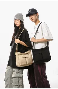 Detail view of large canvas messenger bags in beige and black with utility pockets