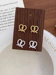 Detail of s925 silver twisted heart knot stud earrings in gold and silver finish