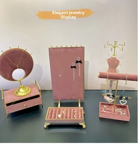 Detail view of pink velvet jewelry display stands with gold metal frames and storage drawers